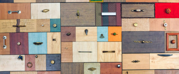 A colorful patchwork of rectangular wooden panels in various shades and textures, each featuring a different style of handle, knob, or decorative hardware.
