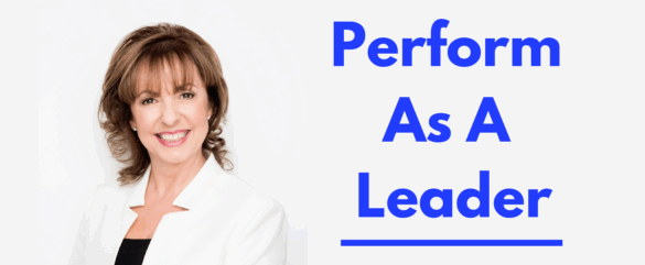 A woman with brown hair, wearing a white blazer and black top, smiles at the camera. Next to her, bold blue text reads: Perform As A Leader. The background is light gray.